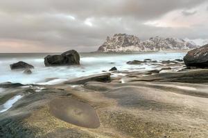 ondas fluindo sobre a praia de utakleiv, ilhas lofoten, noruega no inverno. foto