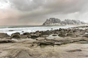 ondas fluindo sobre a praia de utakleiv, ilhas lofoten, noruega no inverno. foto