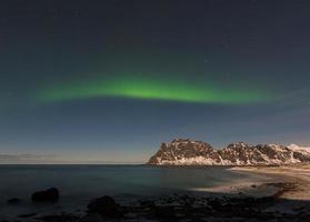 aurora boreal sobre o mar na praia de utakleiv, ilhas lofoten, noruega no inverno. foto