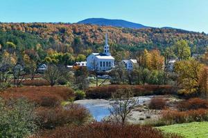 Stowe panorama no final do outono com folhagem colorida e igreja comunitária em vermont. foto