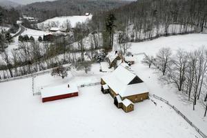 vista aérea de uma casa de fazenda e celeiro na zona rural de vermont em um dia de neve. foto