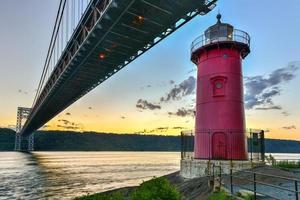 ponte george washington e o pequeno farol vermelho em fort washington park, nova york, ny à noite. foto