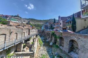 tbilisi, georgia - 10 de julho de 2018 - famosos banhos de enxofre com mesquita islâmica orbeliani, arquitetura tradicional de tiflis, varandas de madeira esculpidas no distrito de abanotubani em tbilisi, georgia. foto