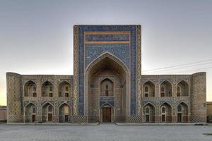 o abdullah khan madrassah ostenta o pátio perfeitamente decorado com rendilhados de azulejos azuis nas paredes em bucara, uzbequistão. foto