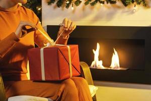 mãos femininas abrindo presente de natal na caixa vermelha foto