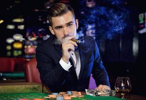 homem bonito rico fumando charuto no cassino foto