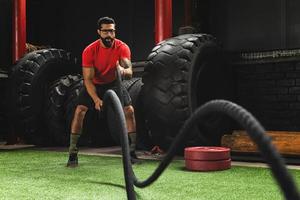 homem está fazendo exercícios de corda de batalha durante seu treino de cross training foto