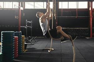 esportista fazendo exercício de escalada de corda no ginásio de treinamento cruzado foto