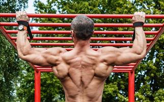 homem fazendo flexões na barra horizontal foto