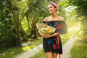 mulher jovem feliz com uma cesta cheia de frutas exóticas foto