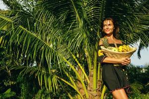 mulher jovem feliz com uma cesta cheia de frutas exóticas foto