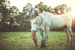 jovem casal feliz e lindo cavalo branco foto