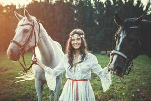 jovem em lindo vestido branco e seus lindos cavalos foto