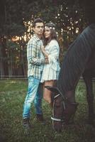 jovem casal abraçado no prado com cavalos foto