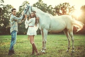 jovem casal feliz e lindo cavalo branco foto