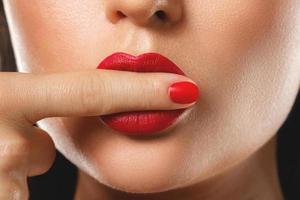 beleza e cosméticos. boca feminina e unhas com batom e manicure vermelho. foto