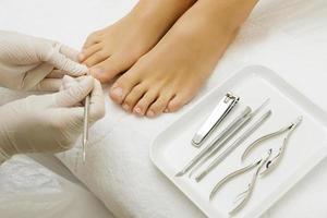 trabalho mestre de pedicure. close-up de unhas femininas e mãos de pedicuro em luvas com ferramentas especiais. foto