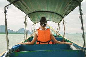 jovem mulher no barco de cauda longa durante suas férias na tailândia foto