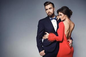 mulher de vestido vermelho lindo e homem vestindo terno clássico azul com gravata borboleta. foto