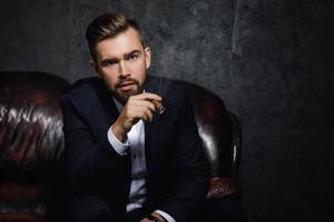 retrato de homem rico bonito está fumando charuto foto