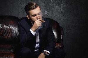 retrato de homem rico bonito está fumando charuto foto