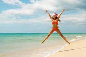 mulher vestindo biquíni e chapéu de natal na praia. férias de inverno nos países quentes. foto