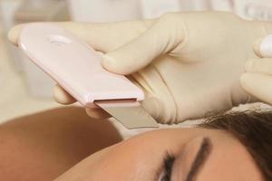 mulher durante salão de beleza spa profissional durante procedimento de limpeza facial ultra-sônica foto