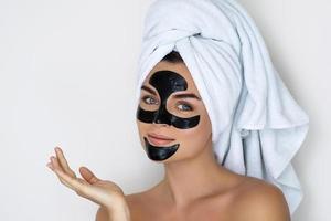 mulher jovem e bonita com máscara peel-off preta no rosto foto