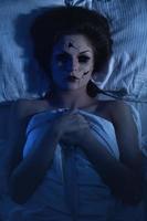 boneca falante de porcelana assustadora segurando faca e deitada na cama foto
