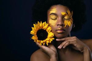 mulher africana com um girassol e maquiagem criativa no rosto foto