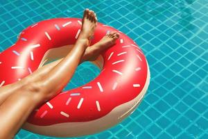pernas femininas e anel de natação inflável em forma de rosquinha foto