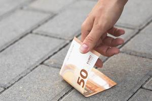 mulher está pegando notas de cinquenta euros do chão. foto