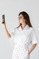 jovem mulher tomando selfie em fundo cinza foto