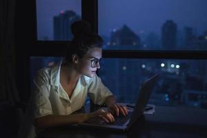 mulher está trabalhando com o laptop em casa durante a noite. foto