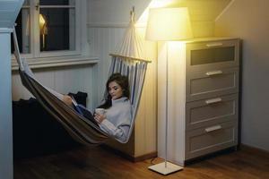 mulher deitada na rede e lendo livro foto