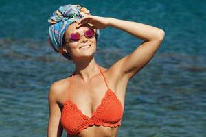 mulher de biquíni e óculos de sol na praia foto
