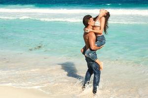 lindo casal vestindo jeans na praia tropical foto