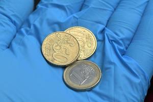 moedas de euro na mão com luva azul foto