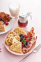 café da manhã do dia dos namorados com waffles em forma de coração, bacon e frutas vermelhas foto