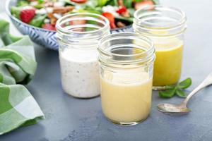 variedade de molhos para salada em potes de vidro foto