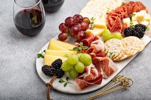 tábua de charcutaria de verão com queijo, carne e fruta foto