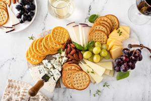tábua de queijos com biscoitos, nozes e uvas foto