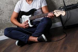 cara barbudo elegante com guitarra contra a parede de concreto foto