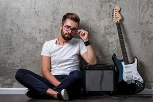 cara barbudo elegante com guitarra contra a parede de concreto foto