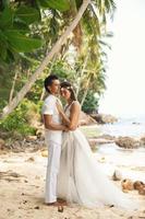 jovem e lindo casal está comemorando casamento na praia foto