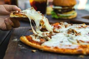 deliciosa pizza com queijo mussarela, carne picada e bacon foto