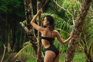 mulher posando ao lado de árvore na praia tropical foto