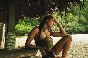 mulher feliz está desfrutando de bebida de coco no bar da praia foto