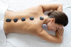 mulher jovem e bonita durante massagem com pedras quentes foto