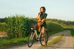 a mulher está pedalando pela estrada secundária no milharal foto